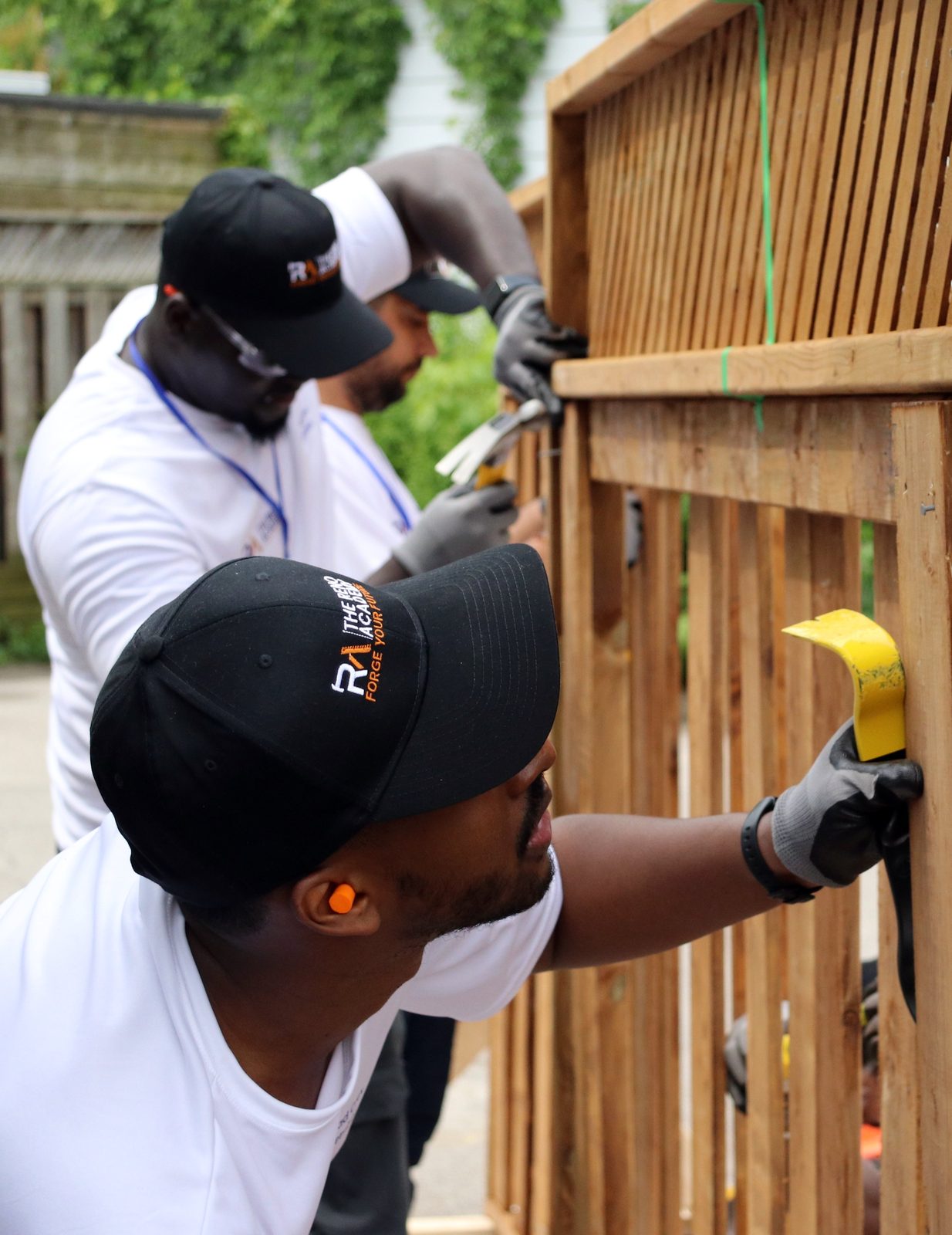 Two Site Squad Bootcamp LE participants hammering fence panels during outdoor trades training in Toronto