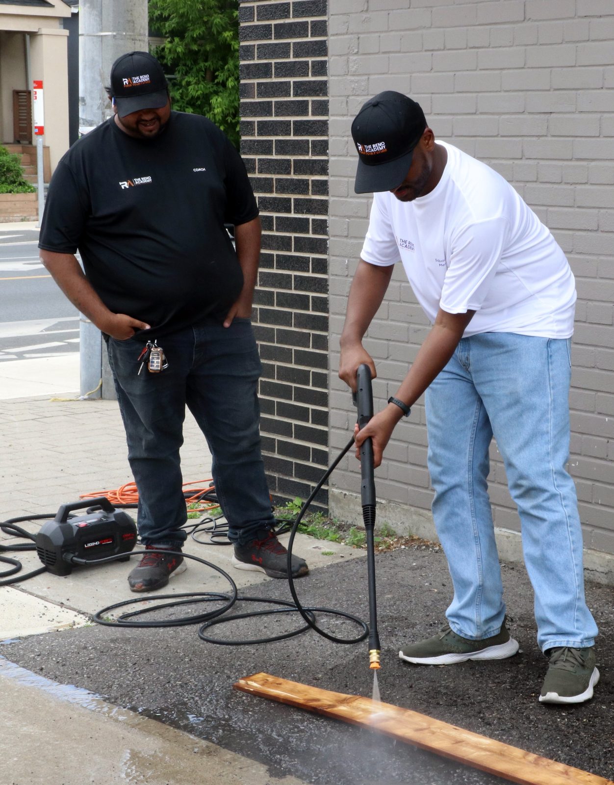 Reno Academy student practising pressure washing a wood board with coach supervision during outdoor trades training in the GTA