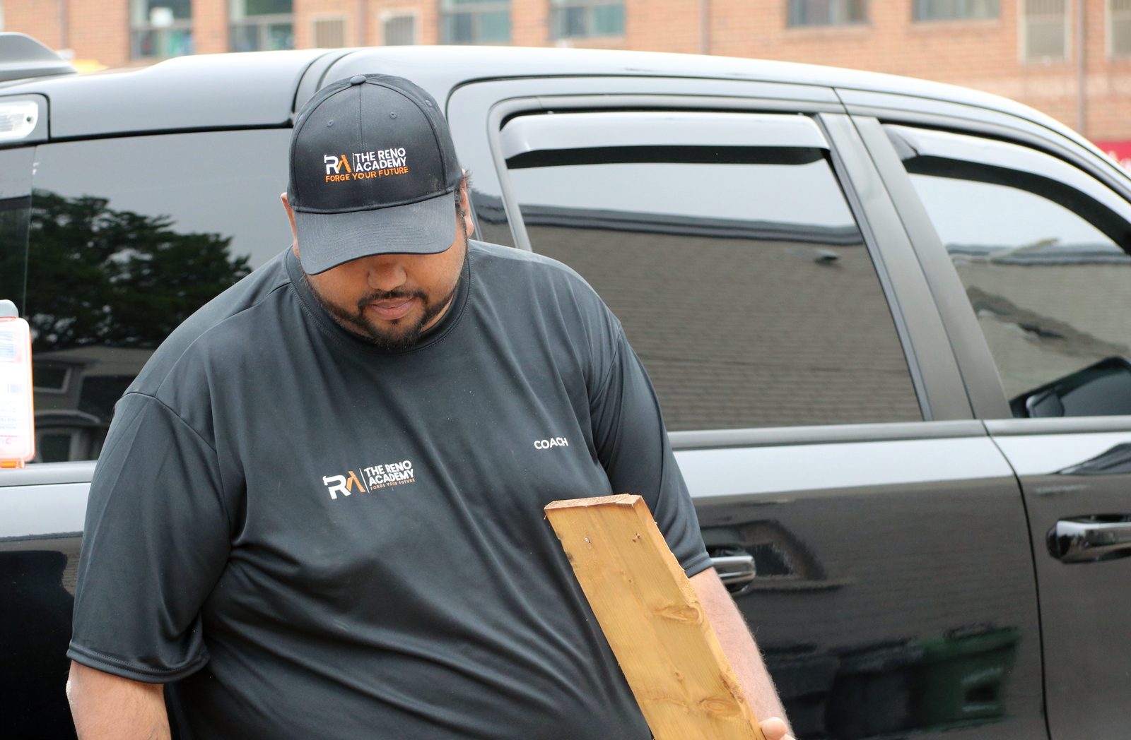 Reno Academy coach carrying lumber at a Toronto trades training site