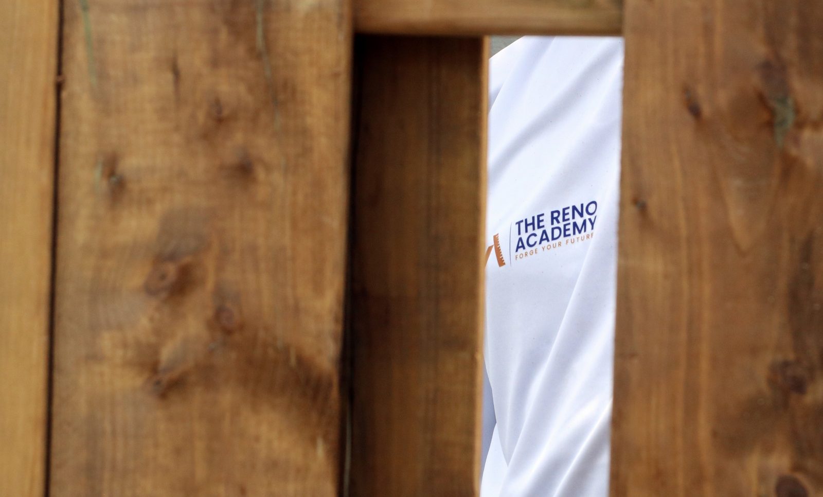 The Reno Academy logo visible through cedar fence boards at a Toronto trades training site